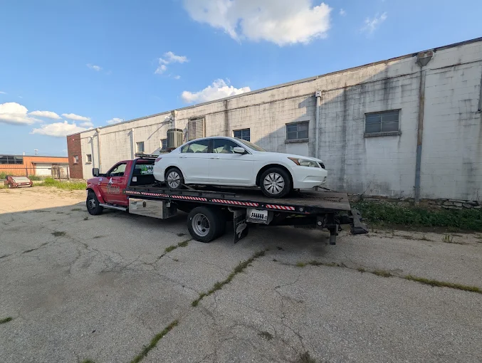 Titan Tow & Repair red flatbed tow truck hauling a white Honda Accord sedan on a light-duty tow in Kansas City, MO